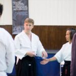 The teacher points out the importance of how to land your hand in order to draw your partner forward